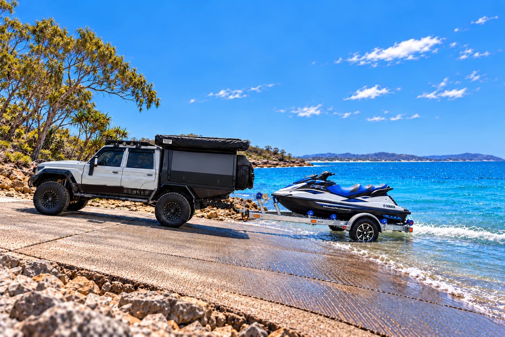 A 4x4 with a canopy backing a jet ski on its trailer down a boat ramp into a clear blue bay